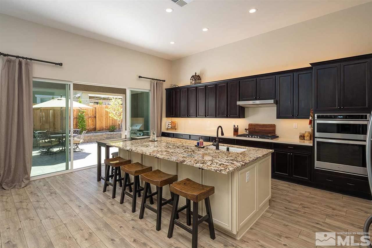 9404 Hawkshead Road Reno, NV 89521 - Photo 4 of 22 a kitchen with kitchen island granite countertop wooden floors and white appliances