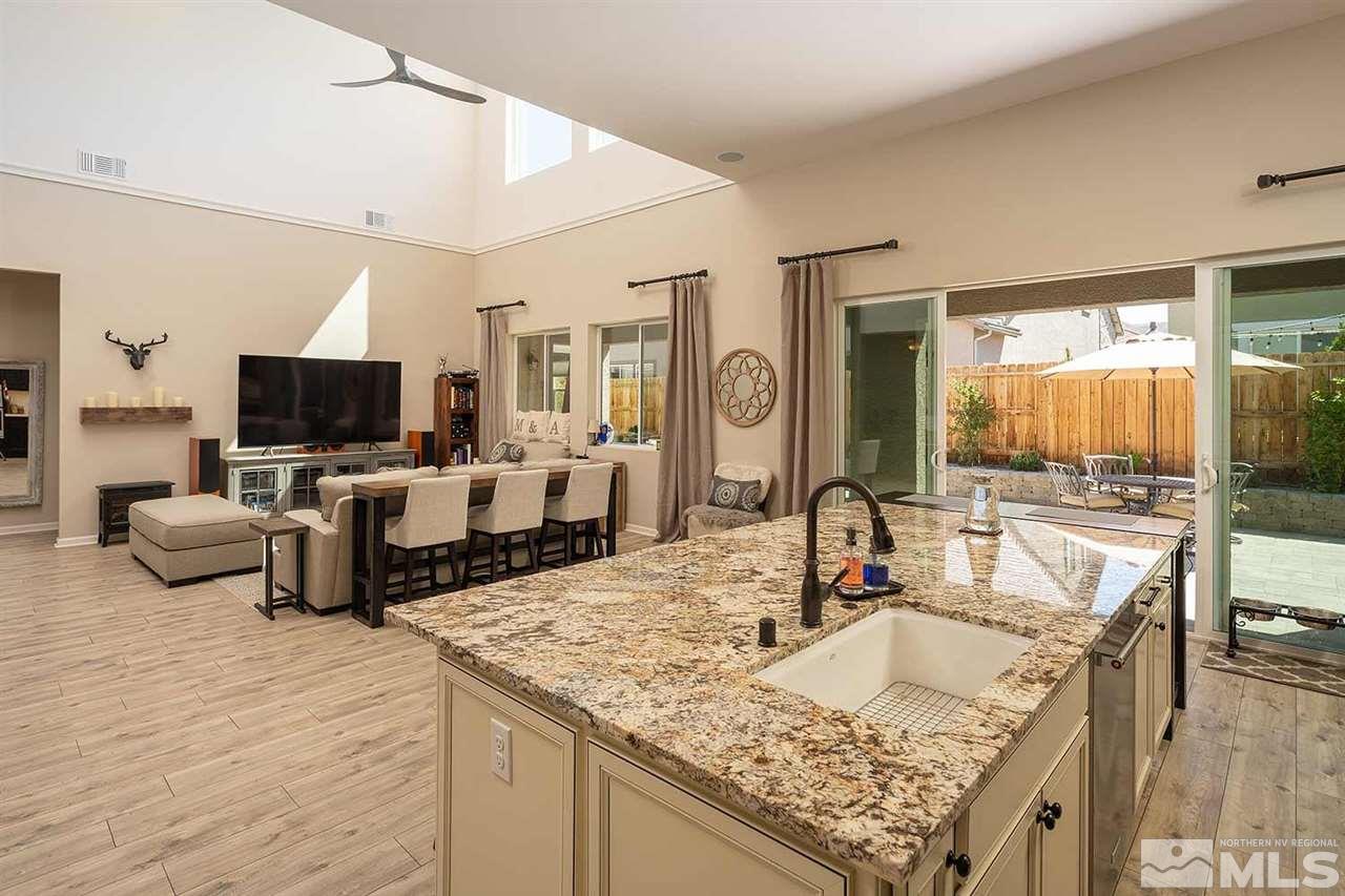 9404 Hawkshead Road Reno, NV 89521 - Photo 6 of 22 a kitchen with granite countertop a sink and a stove top oven with wooden floor