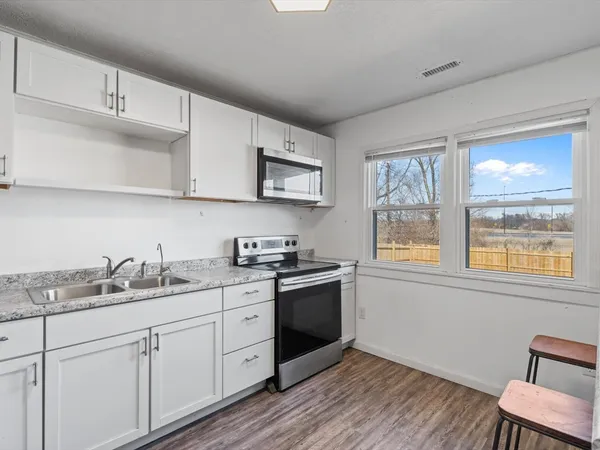 a kitchen with a sink cabinets wooden floor and a window
