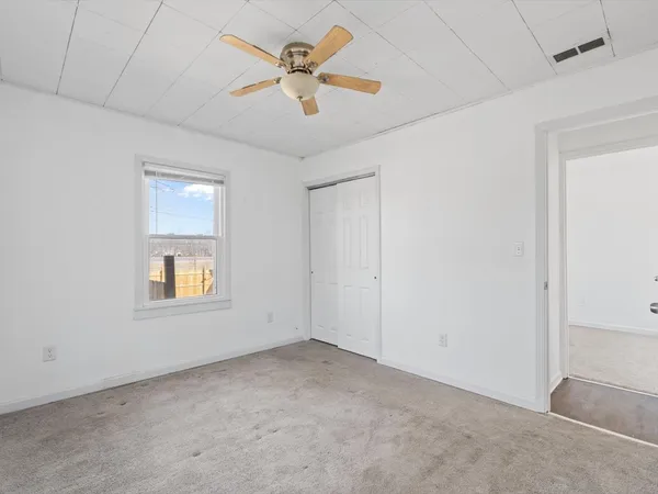 an empty room with a window and a ceiling fan