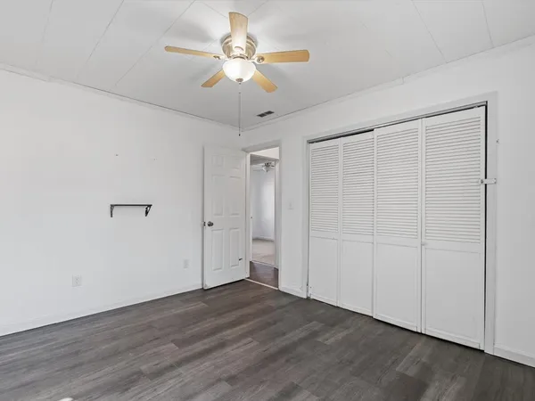 an empty room with wooden floor chandelier fan and closet area