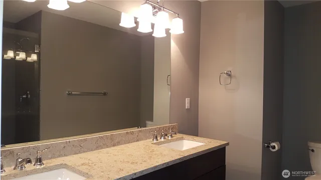 a bathroom with a granite countertop sink toilet and a mirror