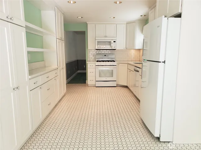 a kitchen with white cabinets and white appliances