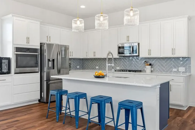 a kitchen with stainless steel appliances a stove a sink a refrigerator and white cabinets