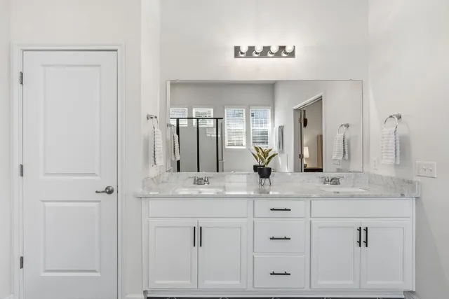 a spacious en suite bathroom with a double vanity sink and mirror