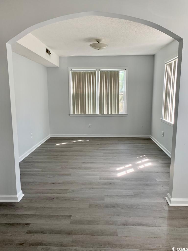105 South Merriman Road, Unit 1 Georgetown, SC 29440 - Photo 11 of 22 Unfurnished room with arched walkways, wood finished floors, and a textured ceiling