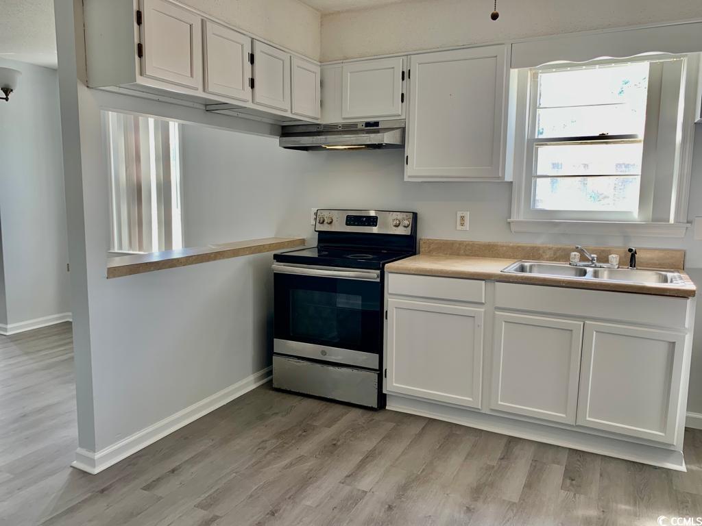 105 South Merriman Road, Unit 1 Georgetown, SC 29440 - Photo 14 of 22 Kitchen featuring stainless steel electric stove, white cabinetry, light countertops, light wood-type flooring, and under cabinet range hood
