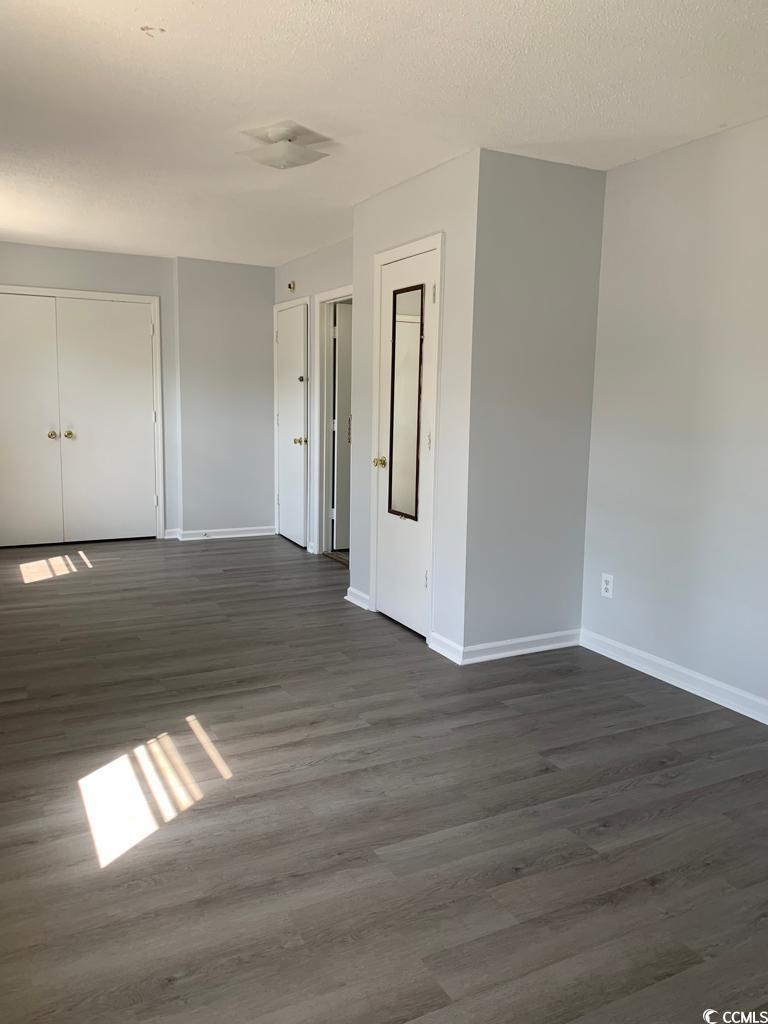 105 South Merriman Road, Unit 1 Georgetown, SC 29440 - Photo 4 of 22 Empty room featuring dark wood finished floors and a textured ceiling