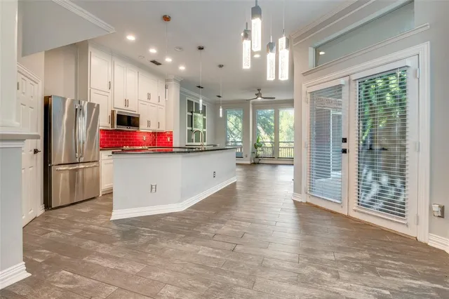 a kitchen view with stainless steel appliances kitchen island granite countertop a refrigerator and a sink