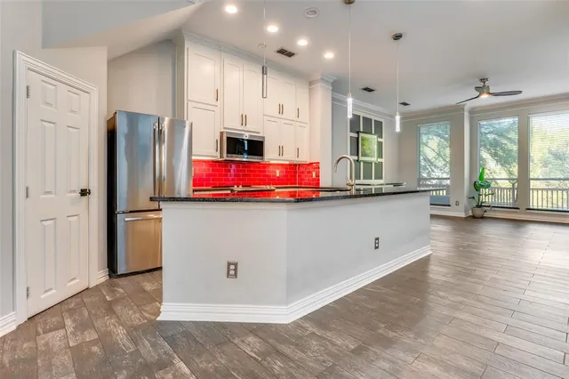 a kitchen with stainless steel appliances granite countertop a refrigerator a stove and a wooden floors