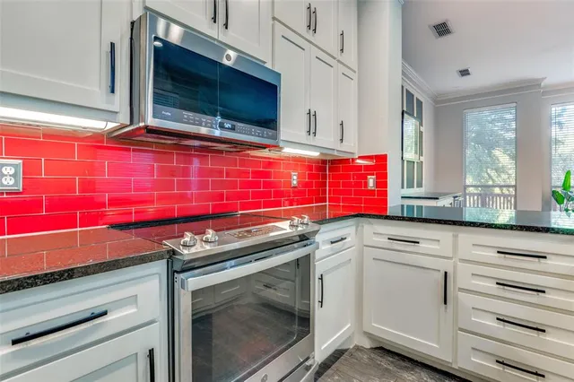 a kitchen with granite countertop white cabinets and stainless steel appliances