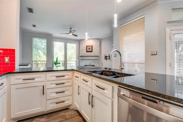a kitchen with granite countertop white cabinets appliances and a window