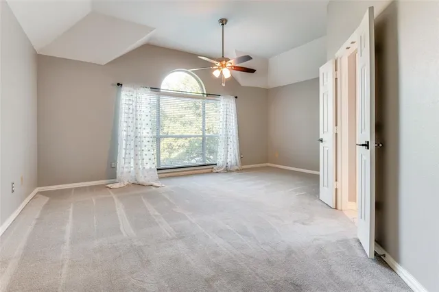 an empty room with windows and ceiling fan
