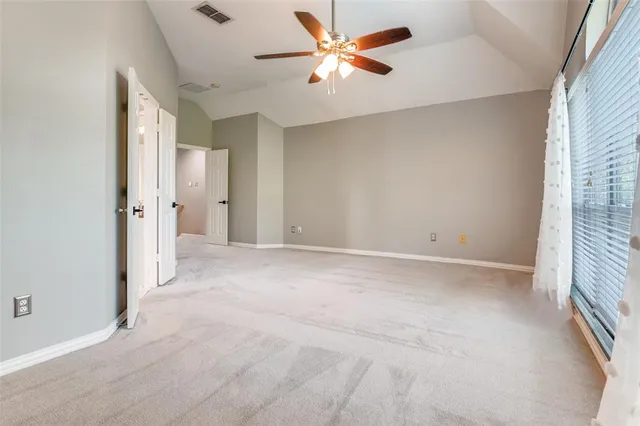 an empty room with closet and a ceiling fan