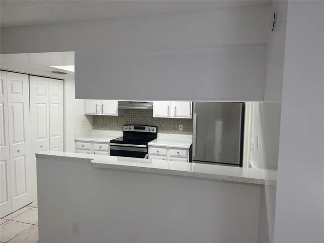 a kitchen with stainless steel appliances a refrigerator a stove and white cabinets