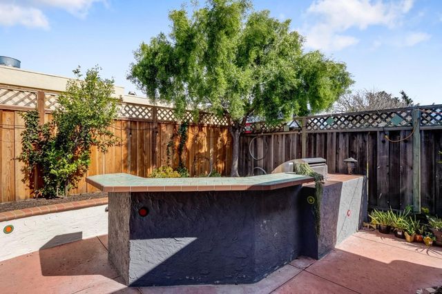 a view of a patio with table and chairs potted plants and a large tree