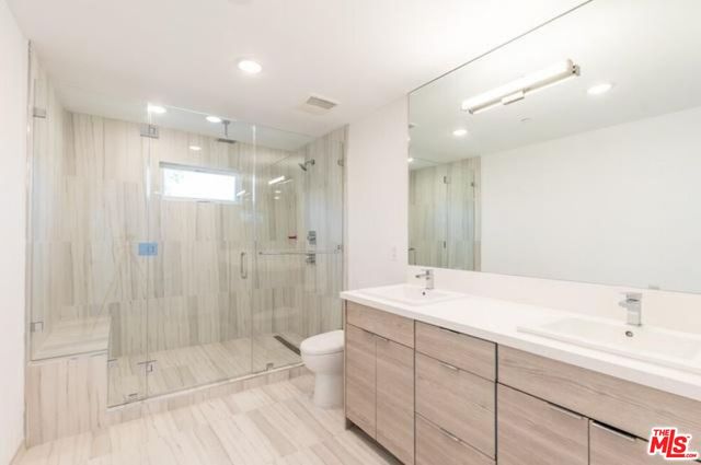 a spacious bathroom with a shower a sink and a mirror
