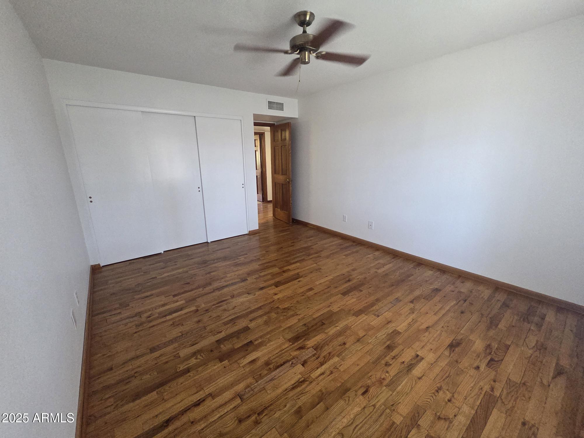 10242 East Spring Creek Road Sun Lakes, AZ 85248 - Photo 21 of 30 a view of empty room with wooden floor and ceiling fan