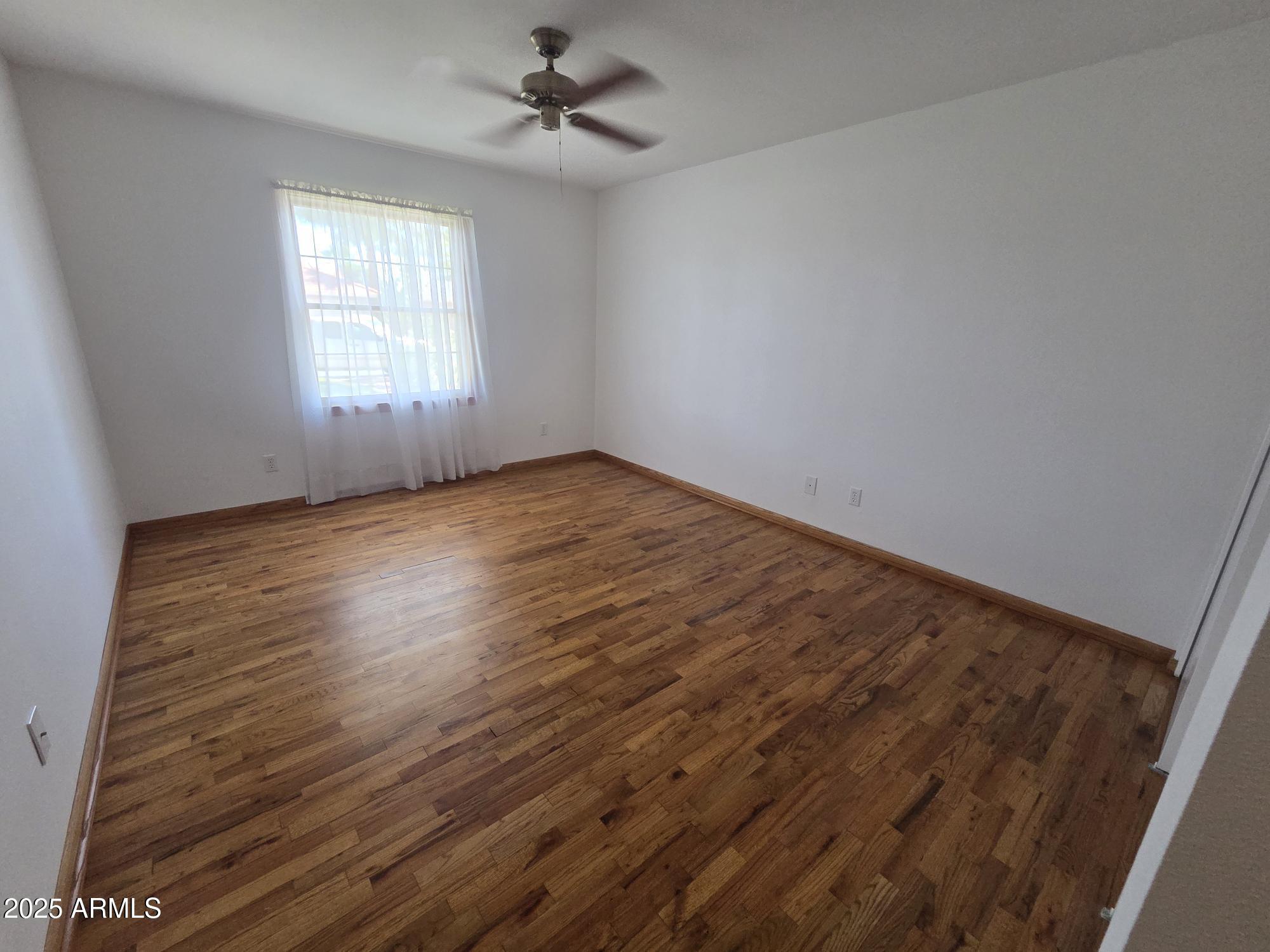 10242 East Spring Creek Road Sun Lakes, AZ 85248 - Photo 22 of 30 wooden floor in an empty room with a window