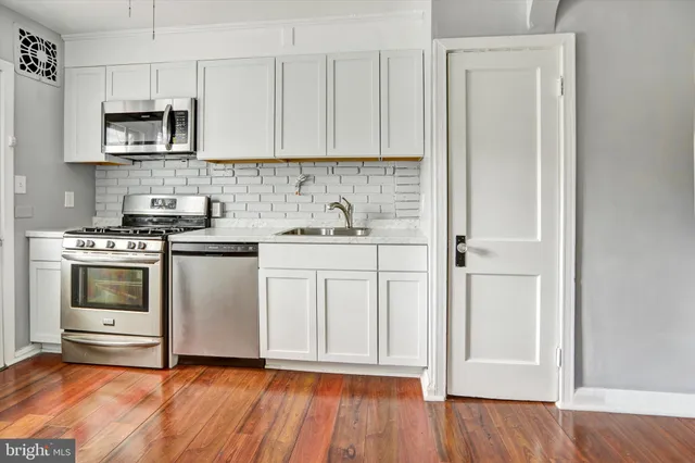 a kitchen with stainless steel appliances white cabinets and a stove top oven