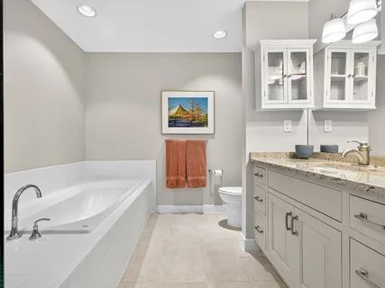 a spacious bathroom with a tub sink and mirror