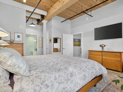 a bedroom with a bed and a flat tv screen on dresser