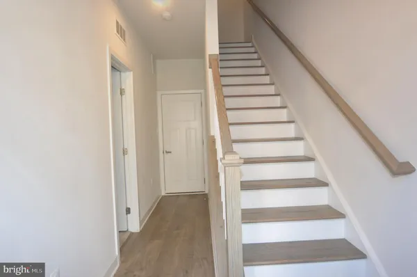 a view of staircase with wooden floor and white walls