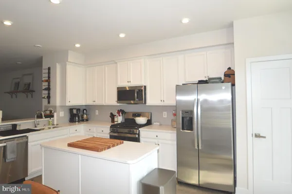 a kitchen with stainless steel appliances granite countertop a refrigerator a sink a stove a microwave and a refrigerator