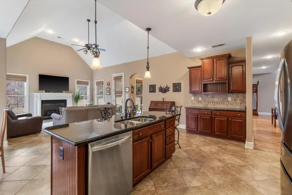 a kitchen with stainless steel appliances kitchen island granite countertop a refrigerator a stove a kitchen island and chairs with wooden floor