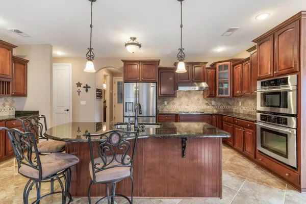 a kitchen with stainless steel appliances granite countertop a sink a stove and a wooden floors