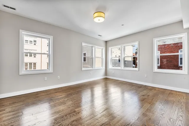 a view of an empty room with a window and wooden floor
