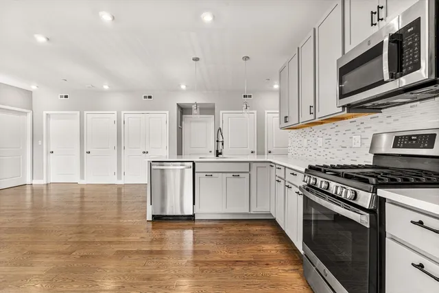 a kitchen with stainless steel appliances granite countertop a stove a sink and a microwave