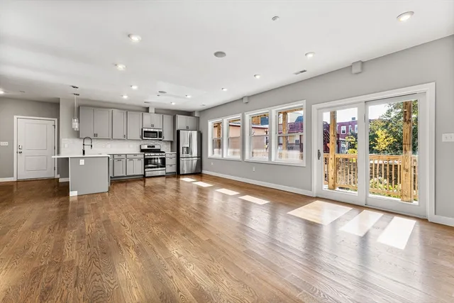 a view of an empty room with a window and wooden floor