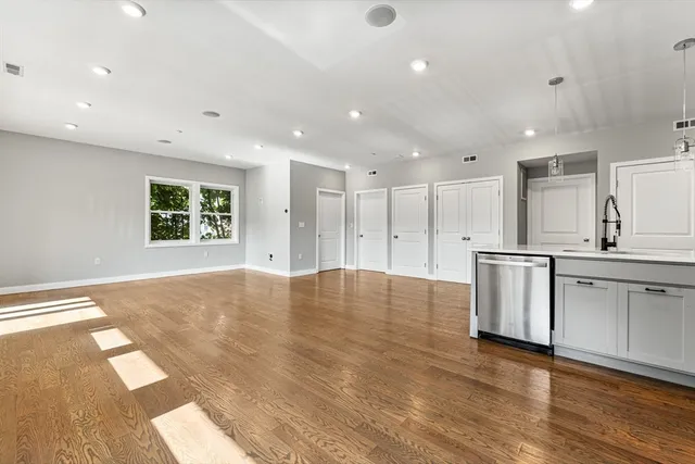 a view of kitchen with stainless steel appliances granite countertop a stove a sink a refrigerator and white cabinets with wooden floor
