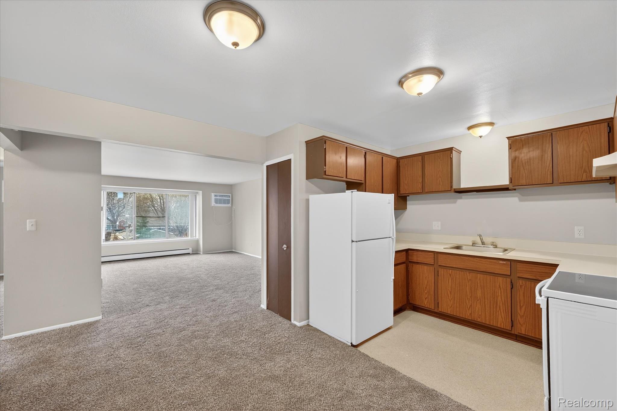 32684 Mound Road, Unit 1 Warren, MI 48092 - Photo 3 of 9 Kitchen with white appliances, light countertops, wood finish cabinets, and light carpet