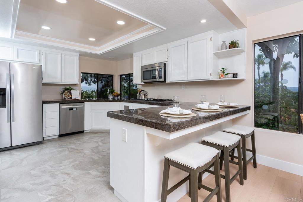 3913 Summer Way Escondido, CA 92025 - Photo 12 of 40 a kitchen with a sink a stove a refrigerator and white cabinets with wooden floor