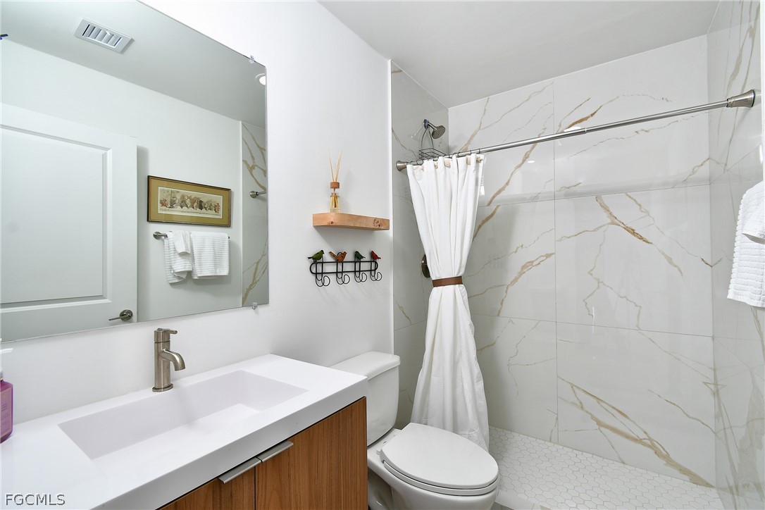 809 Bell Boulevard Lehigh Acres, FL 33974 - Photo 23 of 37 a bathroom with a sink a toilet and shower