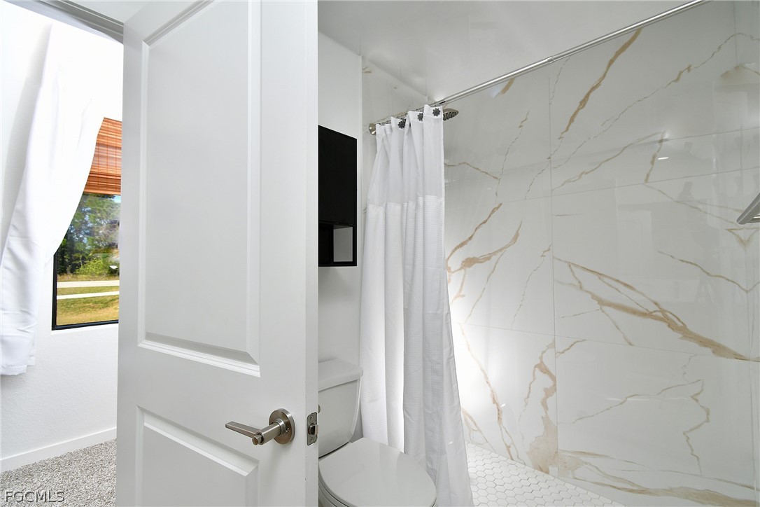 809 Bell Boulevard Lehigh Acres, FL 33974 - Photo 28 of 37 a bathroom with a shower and a toilet