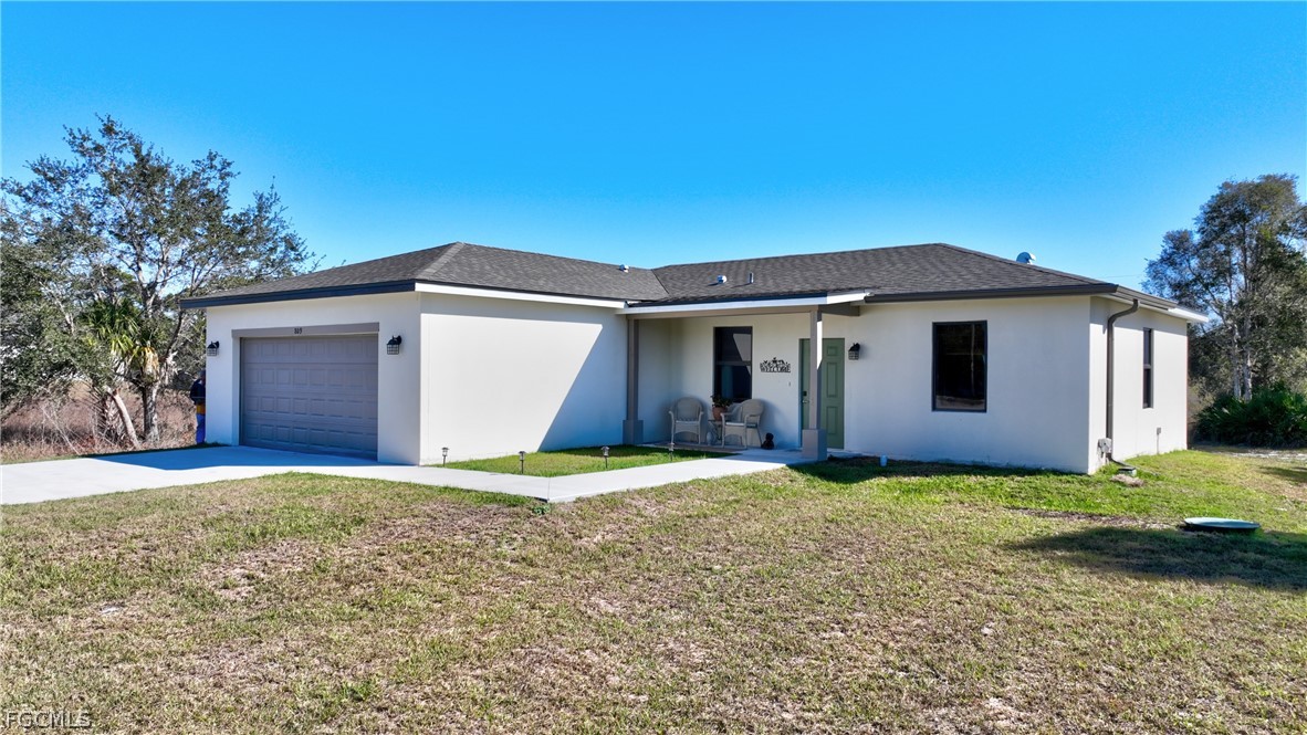809 Bell Boulevard Lehigh Acres, FL 33974 - Photo 6 of 37 a big house with a big yard and large trees
