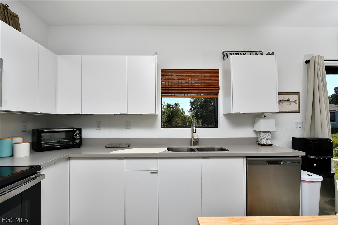 809 Bell Boulevard Lehigh Acres, FL 33974 - Photo 9 of 37 a kitchen with granite countertop a sink a stove and cabinets