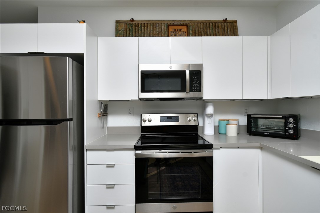 809 Bell Boulevard Lehigh Acres, FL 33974 - Photo 10 of 37 a kitchen with granite countertop a refrigerator stove and microwave