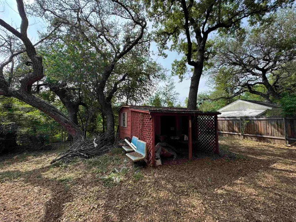 a view of a barn in the backyard with large trees