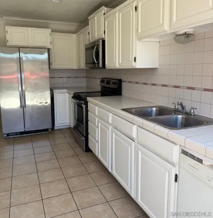a kitchen with stainless steel appliances granite countertop a sink a stove and white cabinets