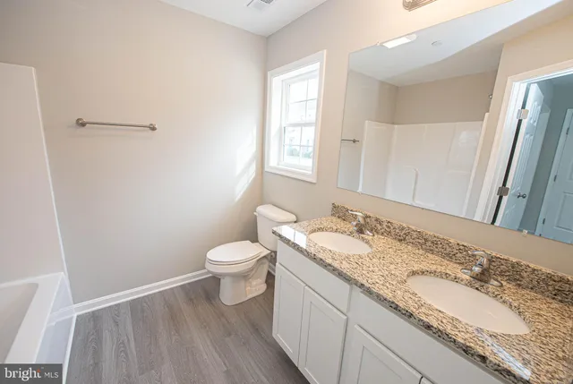 a bathroom with a granite countertop sink a mirror and shower