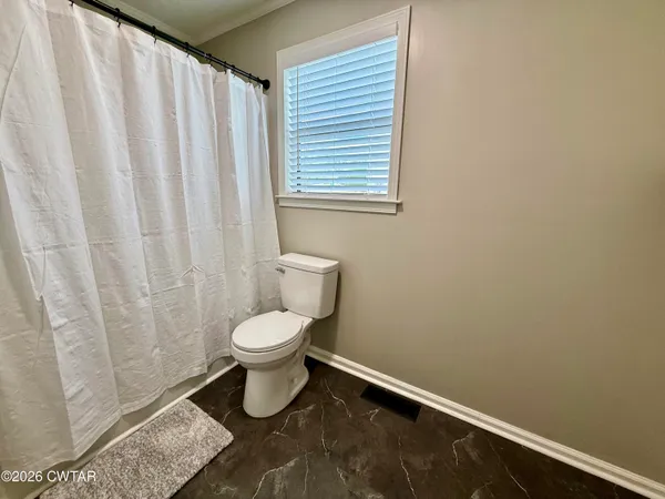 a bathroom with a toilet and a shower curtain