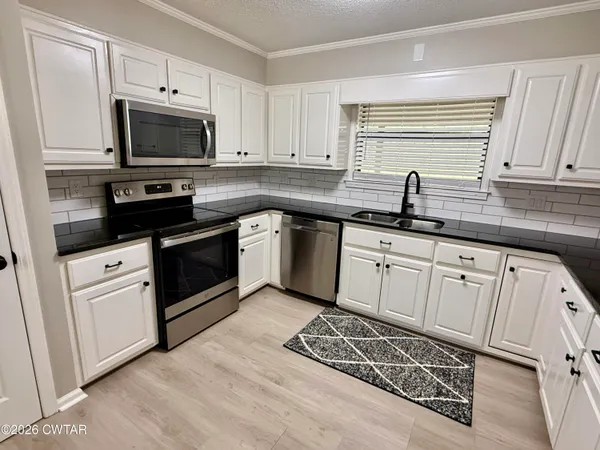 a kitchen with granite countertop a sink cabinets and stainless steel appliances