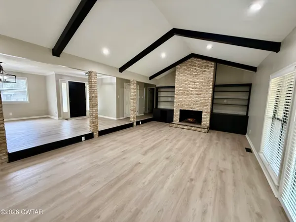 an empty room with a fireplace and wooden floor