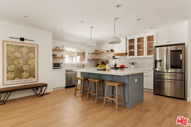 a kitchen with kitchen island a refrigerator a stove a dining table and chairs with wooden floor