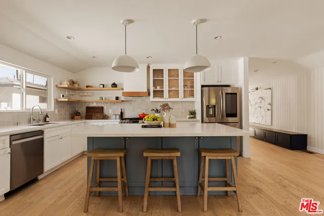 a kitchen with stainless steel appliances granite countertop a sink a stove and chairs