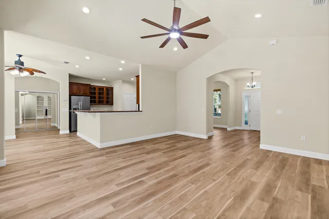 a view of an empty room with a window and wooden floor